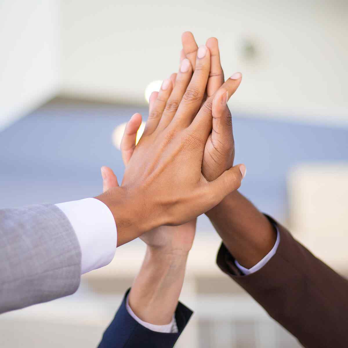 Business colleagues celebrating success and joining hands Business colleagues celebrating success and joining hands. Multiethnic group of man and women giving high five to each other. Achievement concept